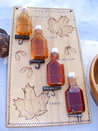 Four glass bottles of maple syrup in varying shades of amber color.