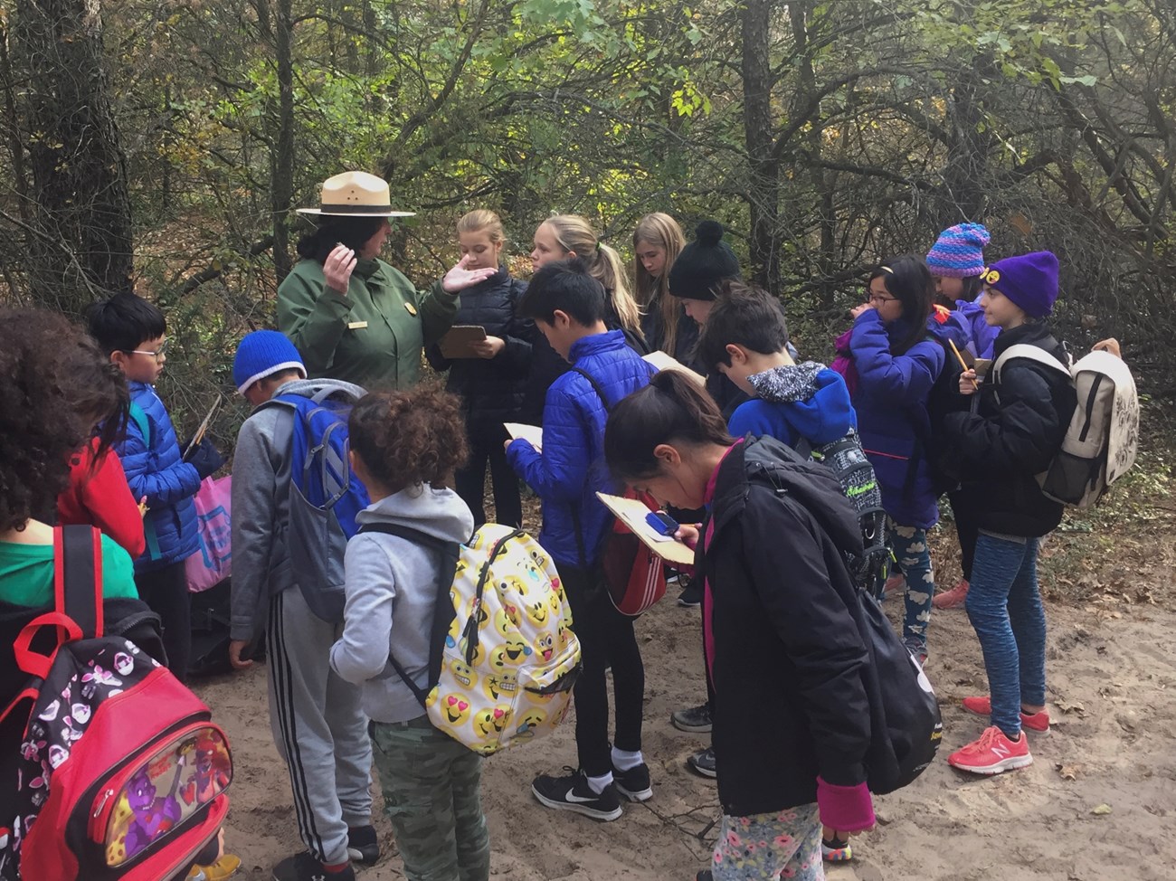 students gathered around a ranger in a jack pine forest