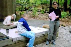 lady standing next to an outdoor stage providing instruction to people working on an art project