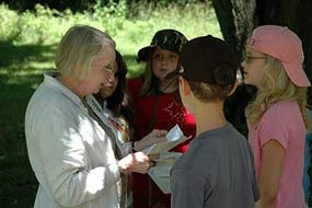 lady standing while talking while kids are watching up close in an outdoor setting