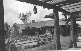 old black and white picture of a log cabin with a landscaped yard
