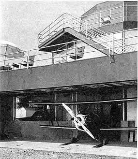 backside of a three story house with a airplane garage as part of the first floor