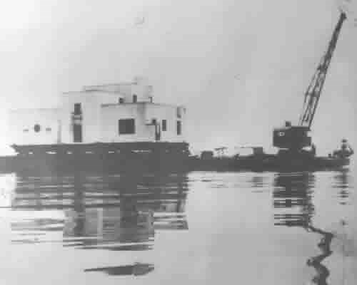 photo from 1935 of house on a barge with a crane in lake michigan