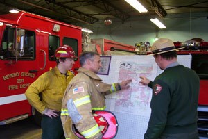 Firefighters in front of  map discussing tactics on a wildfire