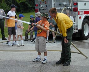 Firefighter and a child spraying water out of fire hose