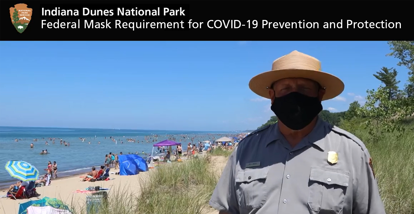 Photo of ranger with mask on at beach.