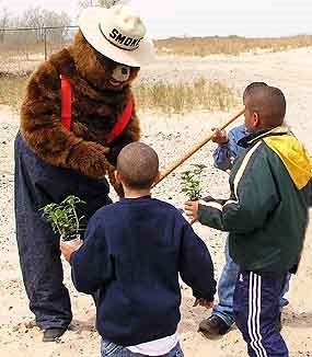 Smokey Bear talking with 3 young boys with sand dune in background