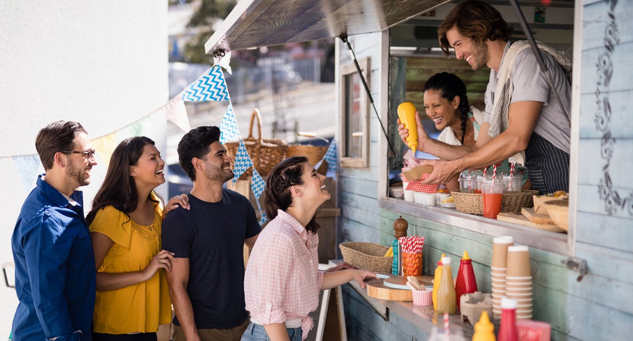 Happy vendor handing meal to customers.