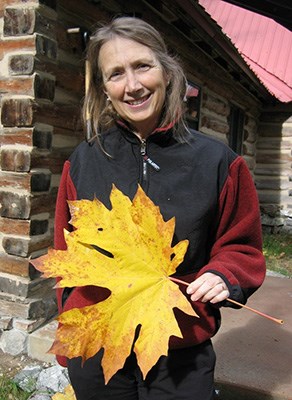 photograph of artist holding an extremely large yellow maple leaf
