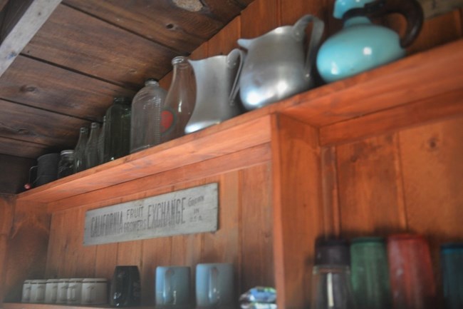 cupboard shelves with a sign behind mugs that reads "California Fruit Growers Exchange Grown in U.S.A."