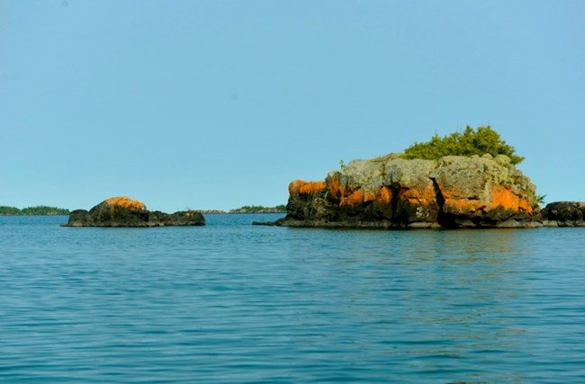 view of two island jutting up out of the blue lake with shrubbery on top
