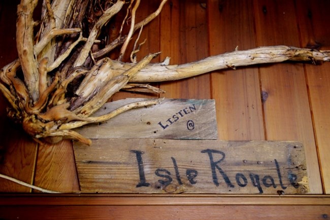 a stick and wooden plank sculpture that proclaims "Listen @ Isle Royale"