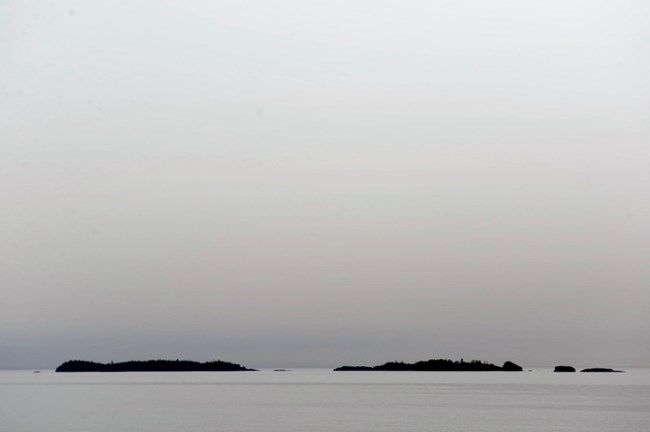 islands in the distance seemingly floating atop a gray lake underneath a gray sky