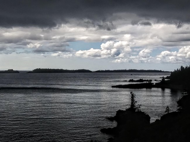 dark clouds over dark lake, blue sky in distance