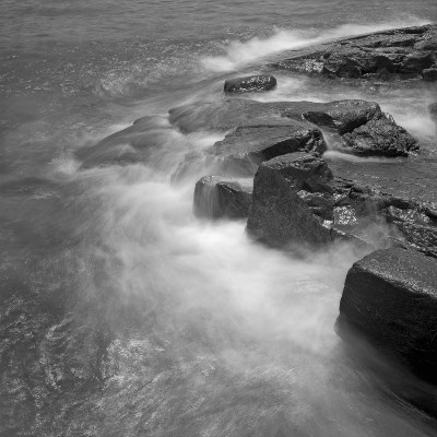 A photograph shows waves lapping over a rock