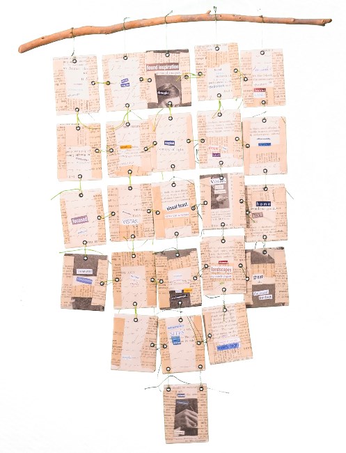 A photograph of a collage which has newspaper backgrounds on individual squares hanging from a stick