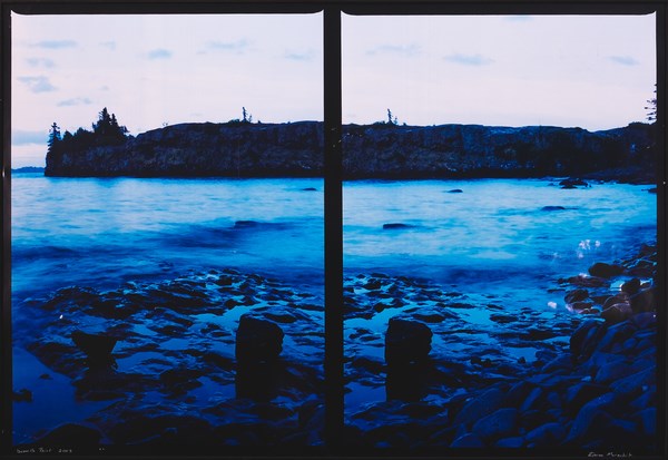 A photograph shows a lake scene through a window