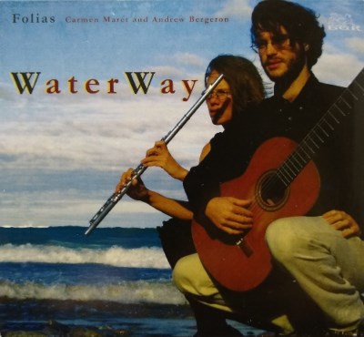 A CD cover shows a man and a woman crouching next to a body of water with waves coming in. He holds a guitar and she a flute.