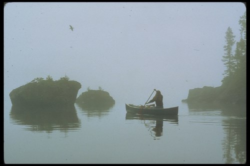 A single woman in a canoe in foggy conditions