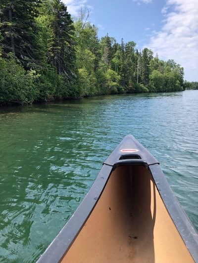 Photo shows the bow of a canoe on open water along the shoreline
