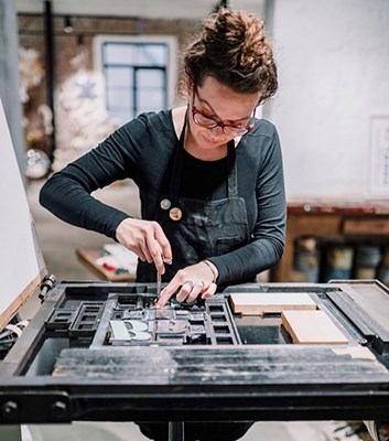artist setting letters on a printing press