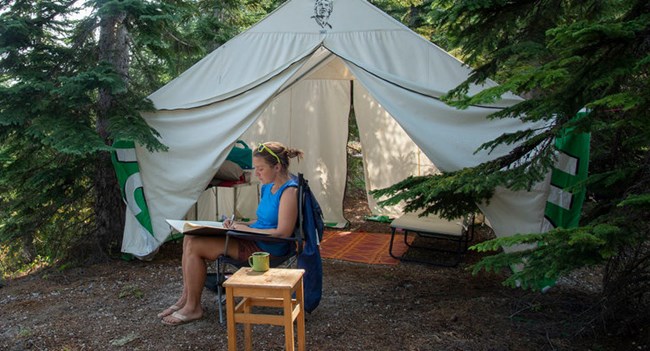 artist sitting in a chair in front of a tent