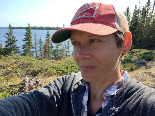 photograph of artist with baseball cap on looking at nature