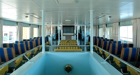 Ranger III's main passenger lounge taken from the top of the rear stairs looking down the two rows of seats on port and starboard with a central row of seats leading to a television monitor.