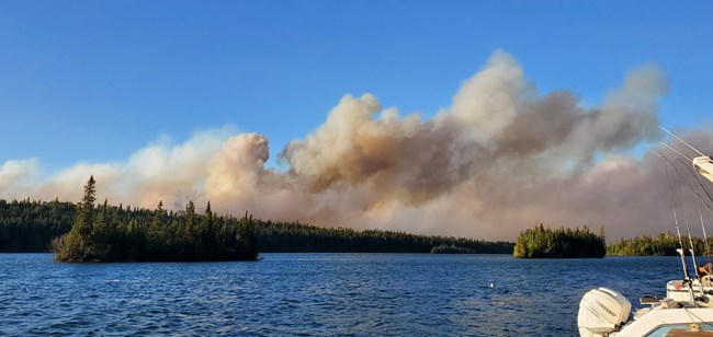 Wildfire burns along Lake Superior with boats docked.