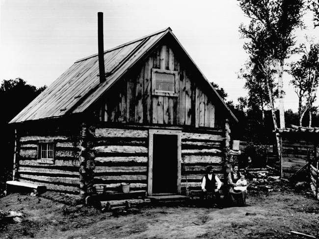 family sitting in front of log cabin