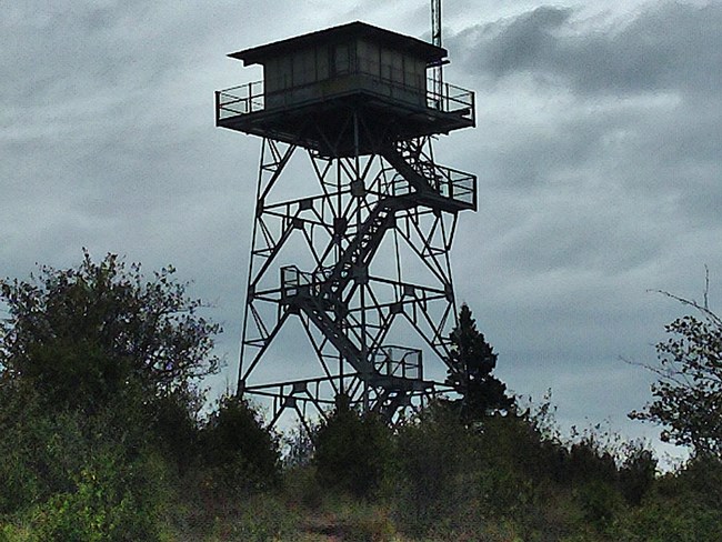 cloudy view of fire tower protruding over the landscape