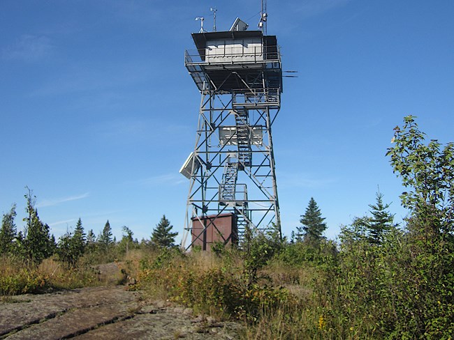 fire tower stands on backdrop of a blue sky