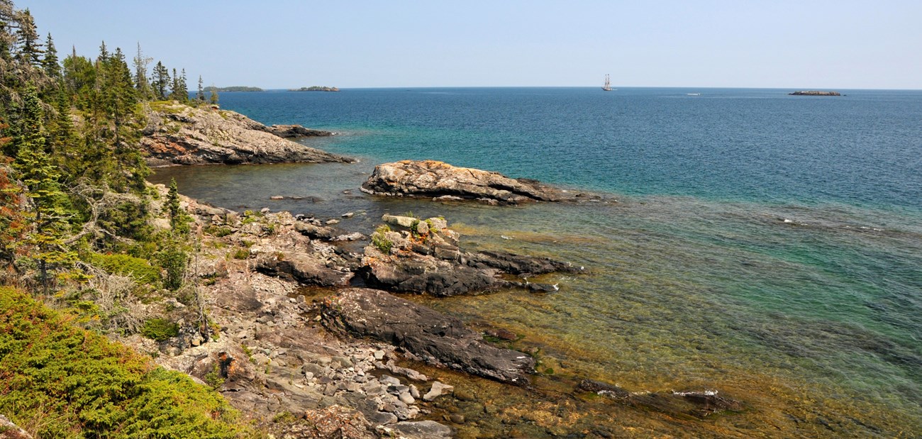 A rocky shoreline on a bright blue lake.