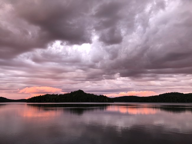 The sunrising over a small island with storm clouds in the sky.