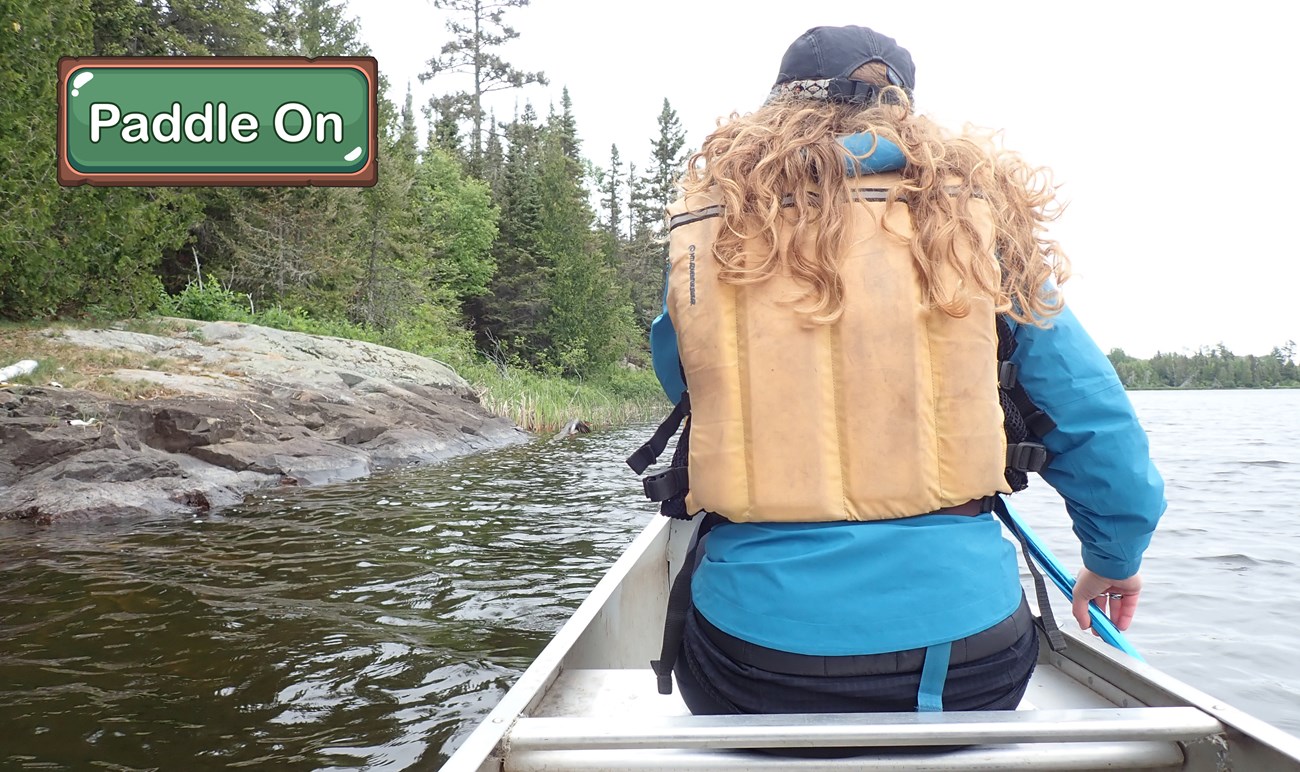 A person paddles a canoe on a lake.