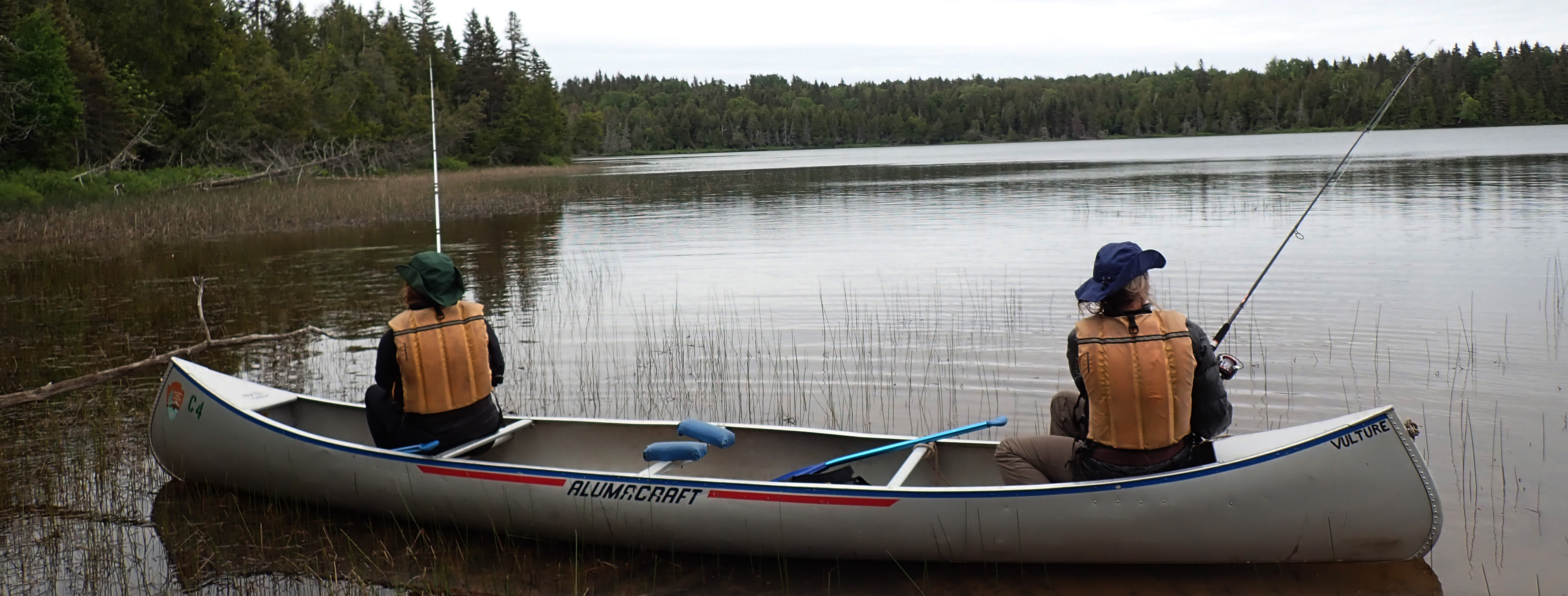 Two people in a canoe fish on a lake.