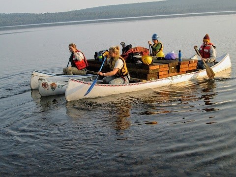 Trail Crew transports boards across Siskiwit Lake strapped to canoes.