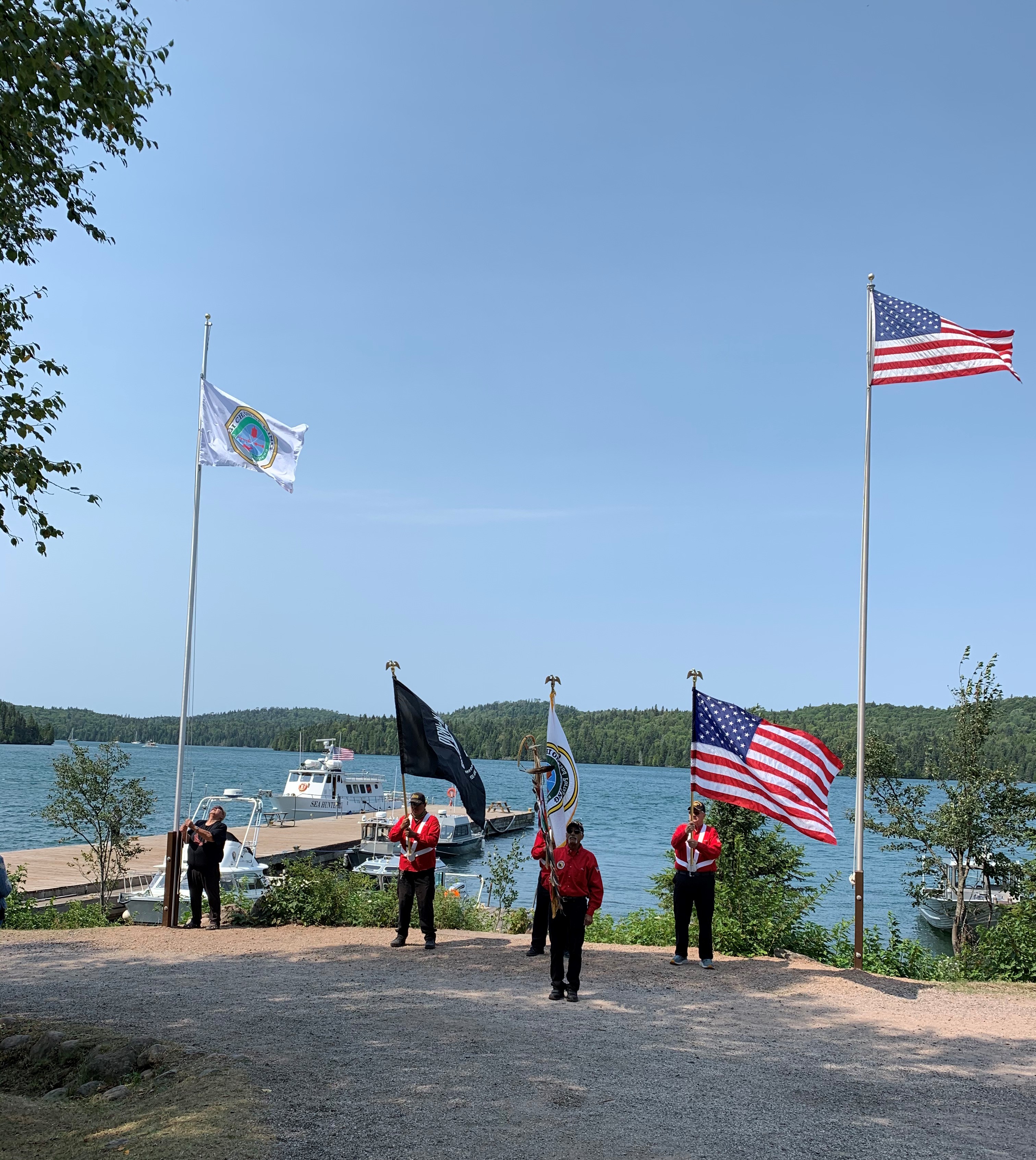 A small group of people stand beneath two flag poles.