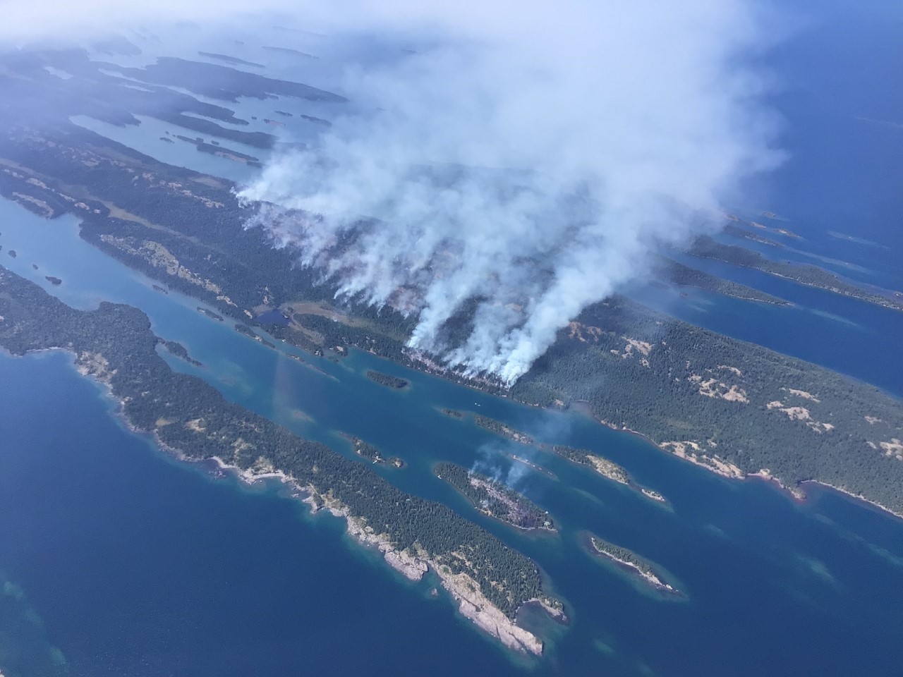 Arial view of wild fire burning on an island in a lake.