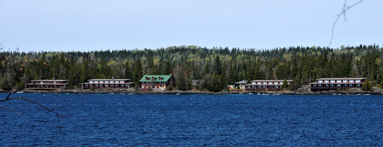 Buildings from the Rock Harbor Lodge sit on the shore of Lake Superior surrounded by forest.