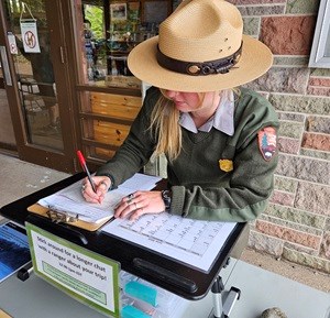 Park Ranger writing a permit at the Rock Harbor Visitor center.