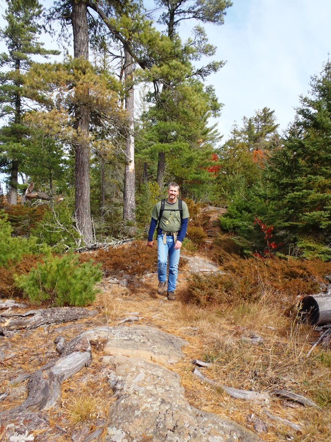 Person hikes on ridge top with trees.