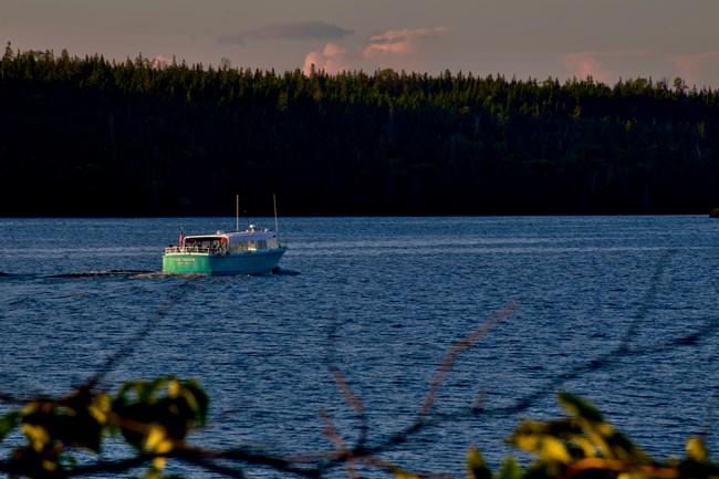 A teal boat labeled Sandy is underway on open water