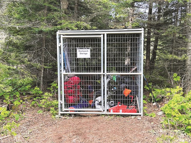 A caged in area filled with bags and backpacks.