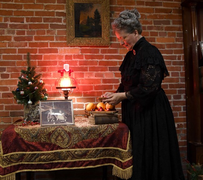 An actress dressed as first lady Lucretia Garfield on stage with props.