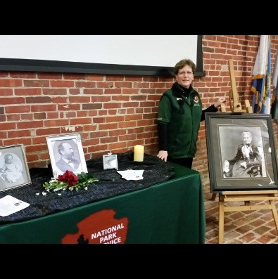 a woman wearing a green shirt is standing next to a table full of pictures