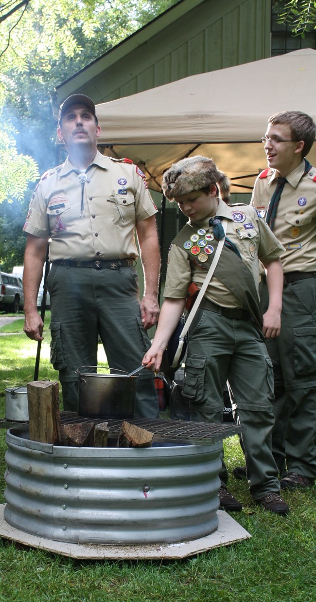 Scouts earning merit badge scouts cooking food over a fire