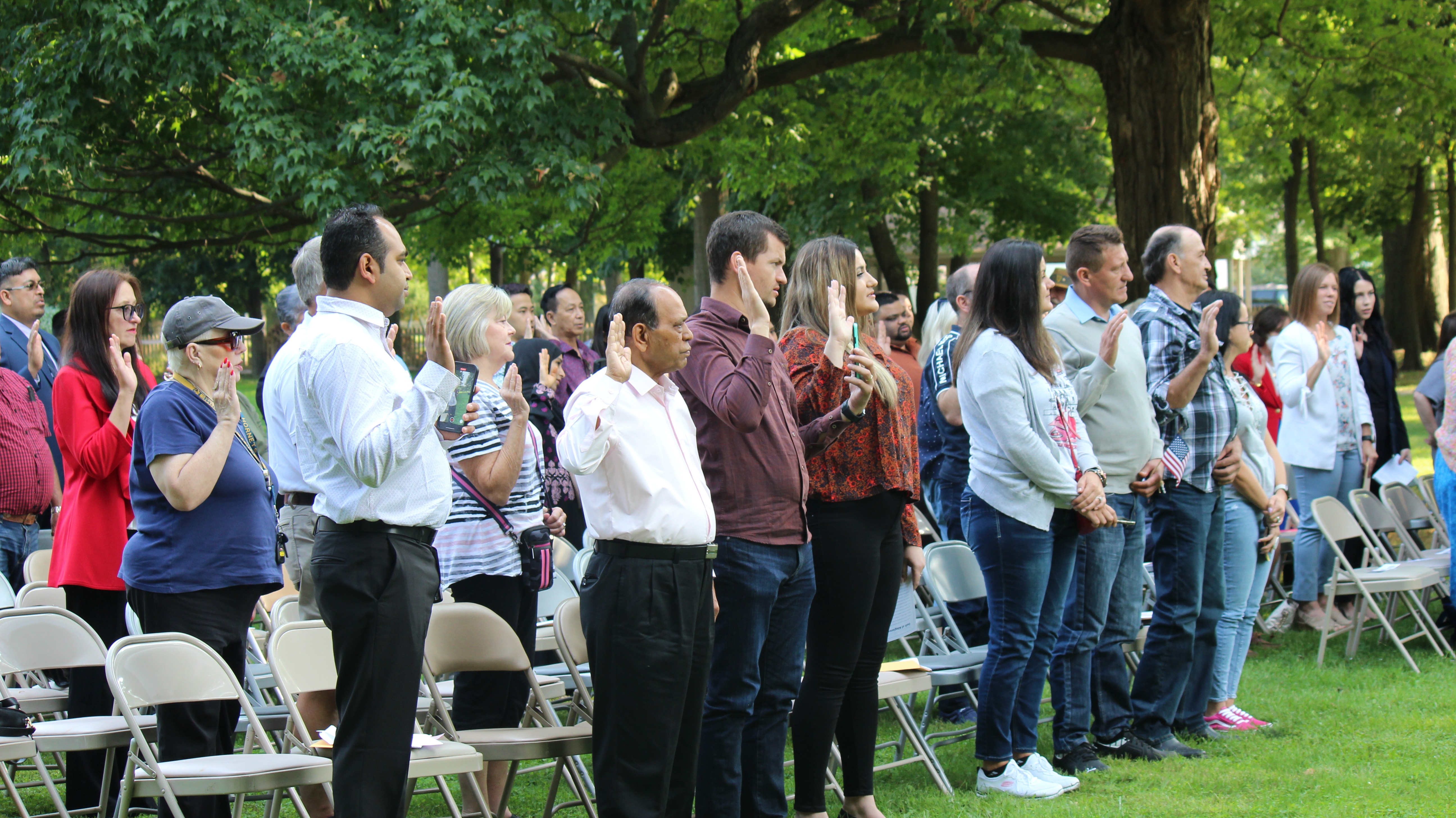 naturalization photo1 A group of people hold up their hands to take the citizenship oath