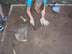 Child using a trowel to dig for artifacts