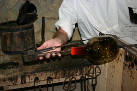 Gassblower forming the neck of a wine bottle